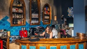 A bar with wooden counter and shelves stocked with bottles and glasses. - Archeo Cafe and Hostel (Istanbul)