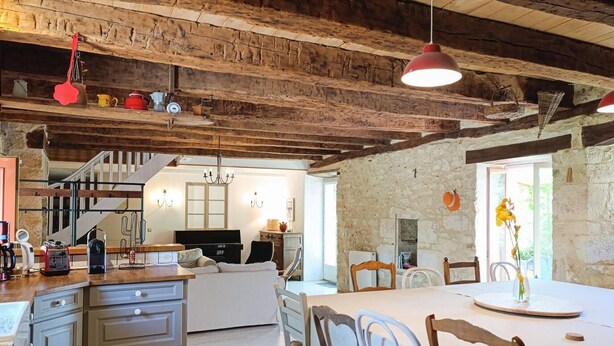 Un interior rústico con vigas de madera a la vista, una zona de cocina y un espacio para comer.