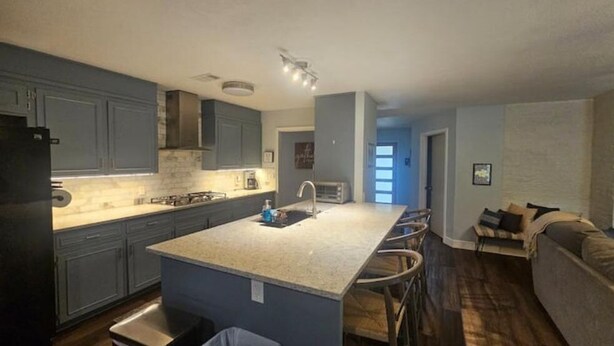 A modern kitchen with a central island, built-in cabinets, and a dining area with bar stools.