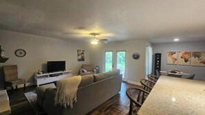 A living room with a sofa, TV, and dining area with chairs and a table.