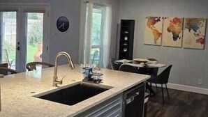A modern kitchen with a central island, grey cabinets, and a built-in dishwasher.