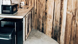 A kitchen with wooden walls, a white tiled backsplash, and modern appliances including a microwave and a coffee maker. - Rustic Grain Bin Lodge with WiFi and AC in Loose Creek, MO (Loose Creek)