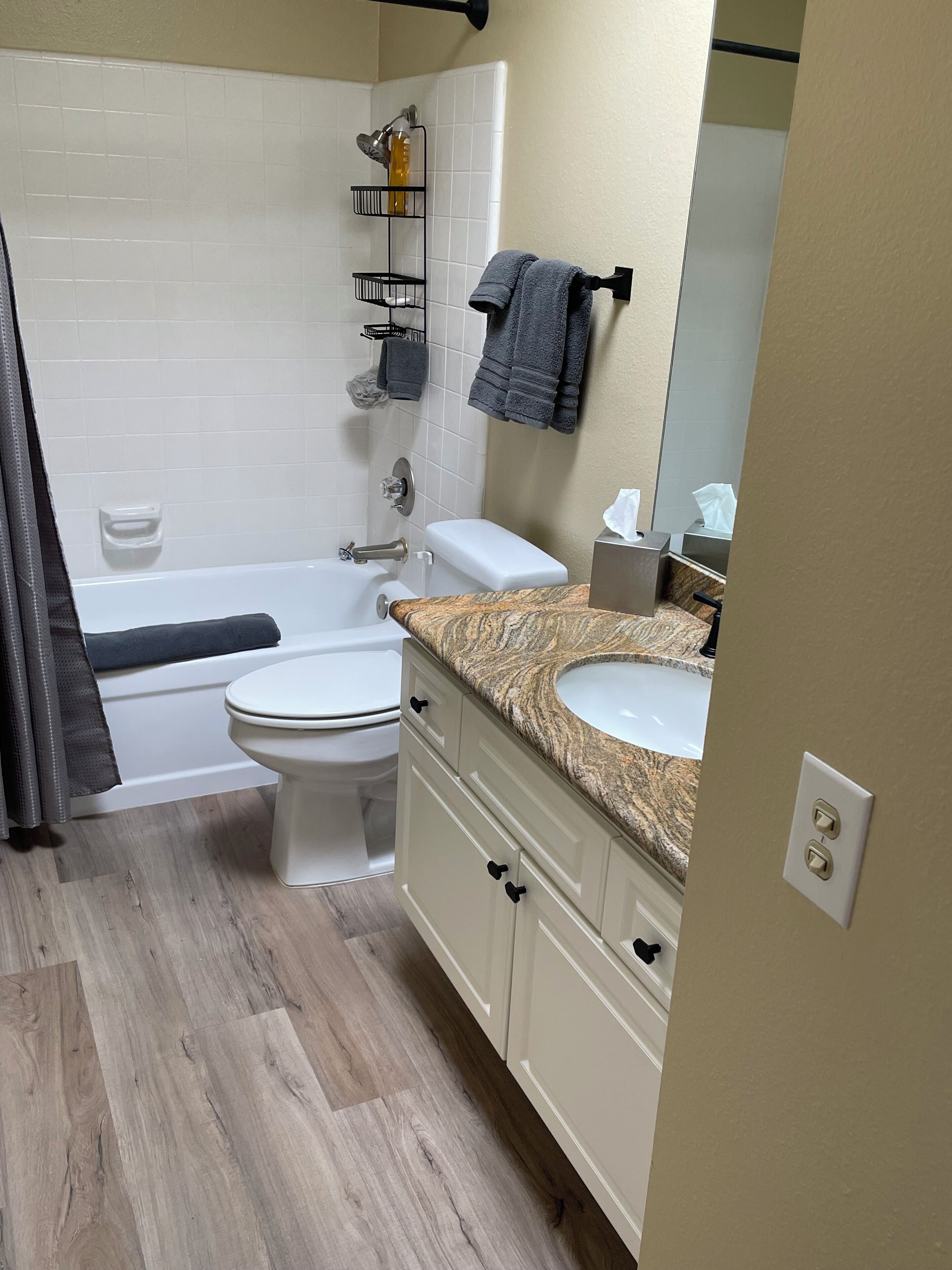 A modern bathroom with a bathtub, toilet, and vanity with a sink.