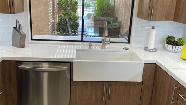 Une cuisine moderne dotée d’un évier encastré, de meubles en bois et d’un lave-vaisselle en acier inoxydable.