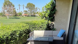 Un espace patio aménagé avec des meubles en osier, notamment un canapé et deux fauteuils, ainsi qu’une table à plateau en verre.