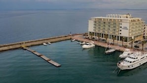 A marina with several yachts docked, a large building labeled "Chocs Chandos" with multiple floors, and a view of the sea in the background. - Chios Chandris (Chios)
