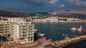 A coastal town with a modern building, marina, and mountains in the background. - Chios Chandris (Chios)