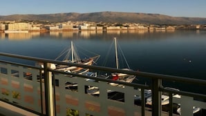 A marina with boats docked, a clear view of the water, and a cityscape with buildings and mountains in the background. - Chios Chandris (Chios)