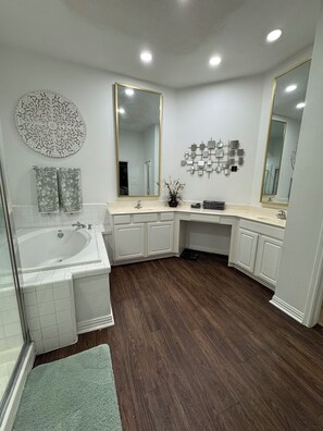 A modern bathroom with a freestanding bathtub, a large mirror, and a decorative wall piece.