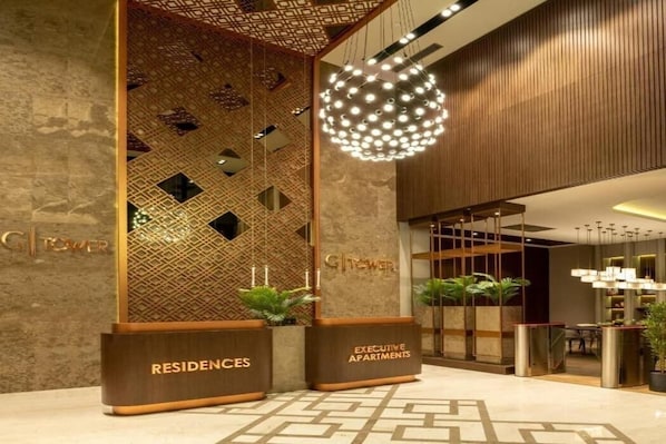 A modern hotel lobby with a geometric patterned wall, a reception desk, and a hanging spherical light fixture. - G Tower Furnished Apartment Rentals Istanbul (Istanbul)