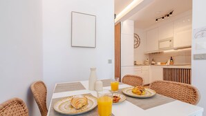 Morgenmadsbord med fletstole, et hvidt bord og tallerkener med croissanter og appelsinjuice.