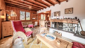A rustic wooden interior with a fireplace, wicker furniture, and a view of the outdoors. - Chalet 'Franclair' with Mountain View, Shared Garden and Wi-Fi (Samoëns)