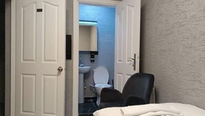 A hotel room with a bed, a chair, a bathroom with a toilet and sink, and a door leading to another room. - Kadıköy Bull Hotel (Istanbul)