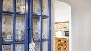 Un buffet bleu avec des portes en verre, contenant de la vaisselle et des verres blancs.