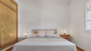 Une chambre à coucher avec un lit, des tables de chevet, une armoire en bois et une fenêtre.