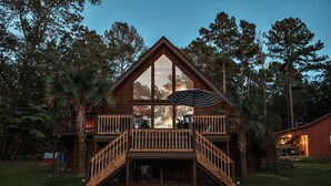 A two-story log cabin with a balcony and a staircase.