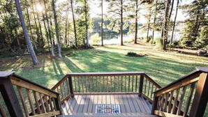 A wooden deck with a view of a grassy area and trees.