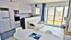 A modern kitchen with white cabinets, a microwave, and a dining area with a white table and chairs. - Apartment 'Fantástico S´agaró' with Shared Pool, Private Terrace and Shared Garden (S'Agaró)
