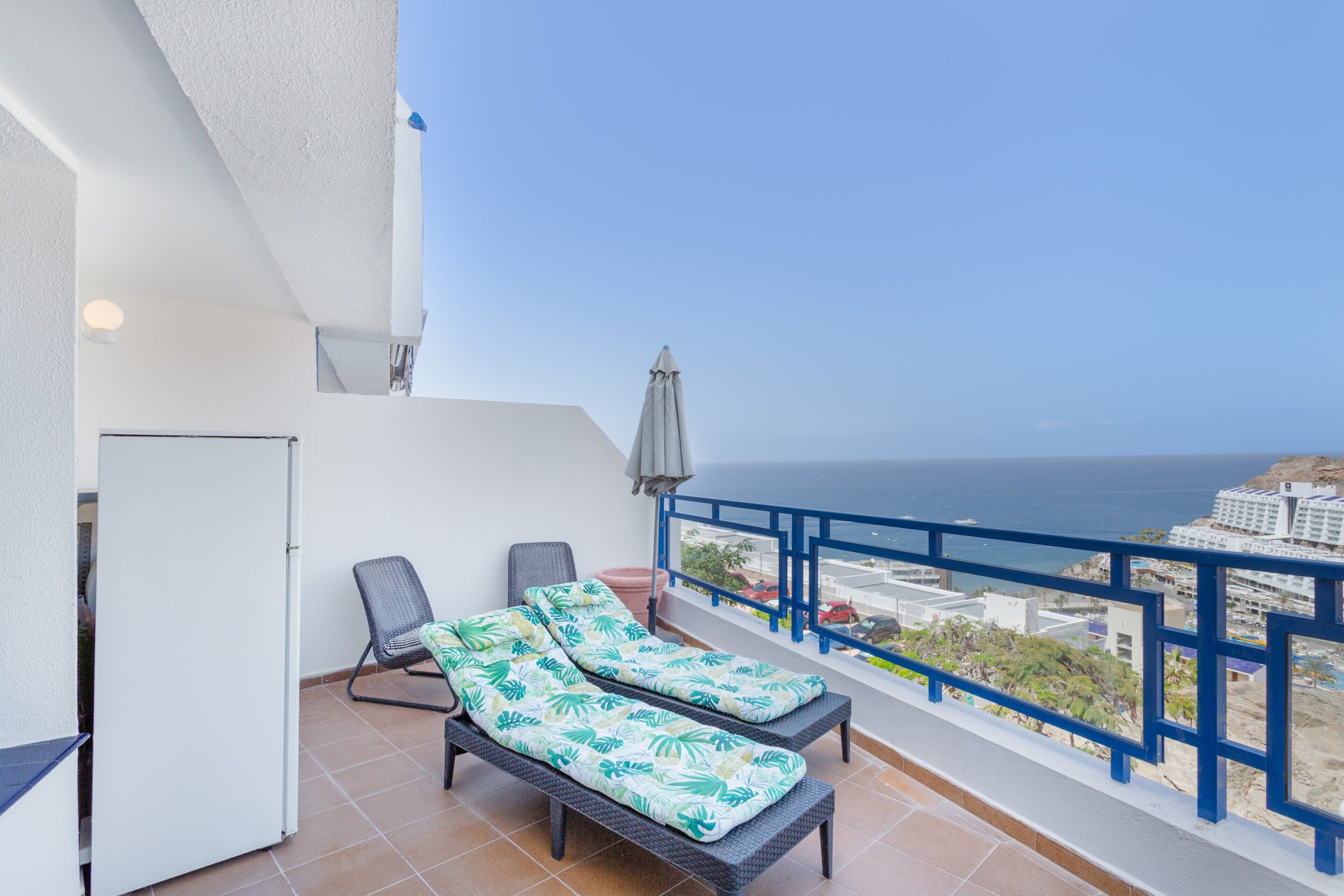 Un balcon équipé de deux fauteuils, d’une petite table et d’un réfrigérateur.