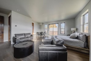 A modern living room with a sofa, ottoman, and a round coffee table. - New 3BR/3BA Condo Steps from Flathead Lake (Lakeside)