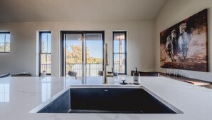 A spacious room with a large white marble sink, a painting on the wall, and a view through the windows. - New 3BR/3BA Condo Steps from Flathead Lake (Lakeside)