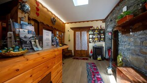 A cozy room with a wooden reception desk, a stone wall, a fireplace, and a skylight. - Room '10' with Shared Terrace, Shared Garden and Wi-Fi (Rhêmes-Notre-Dame)