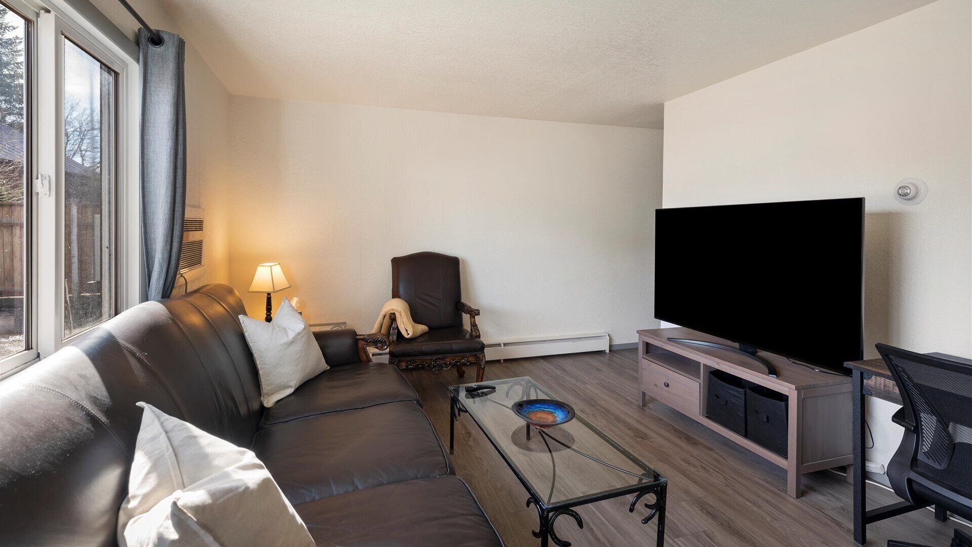 Una sala de estar moderna con un sofá de cuero, un televisor y una mesa de centro de vidrio.