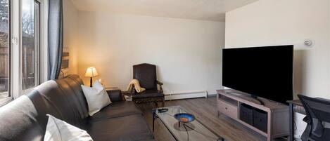 Una sala de estar moderna con un sofá de cuero, un televisor y una mesa de centro de vidrio.