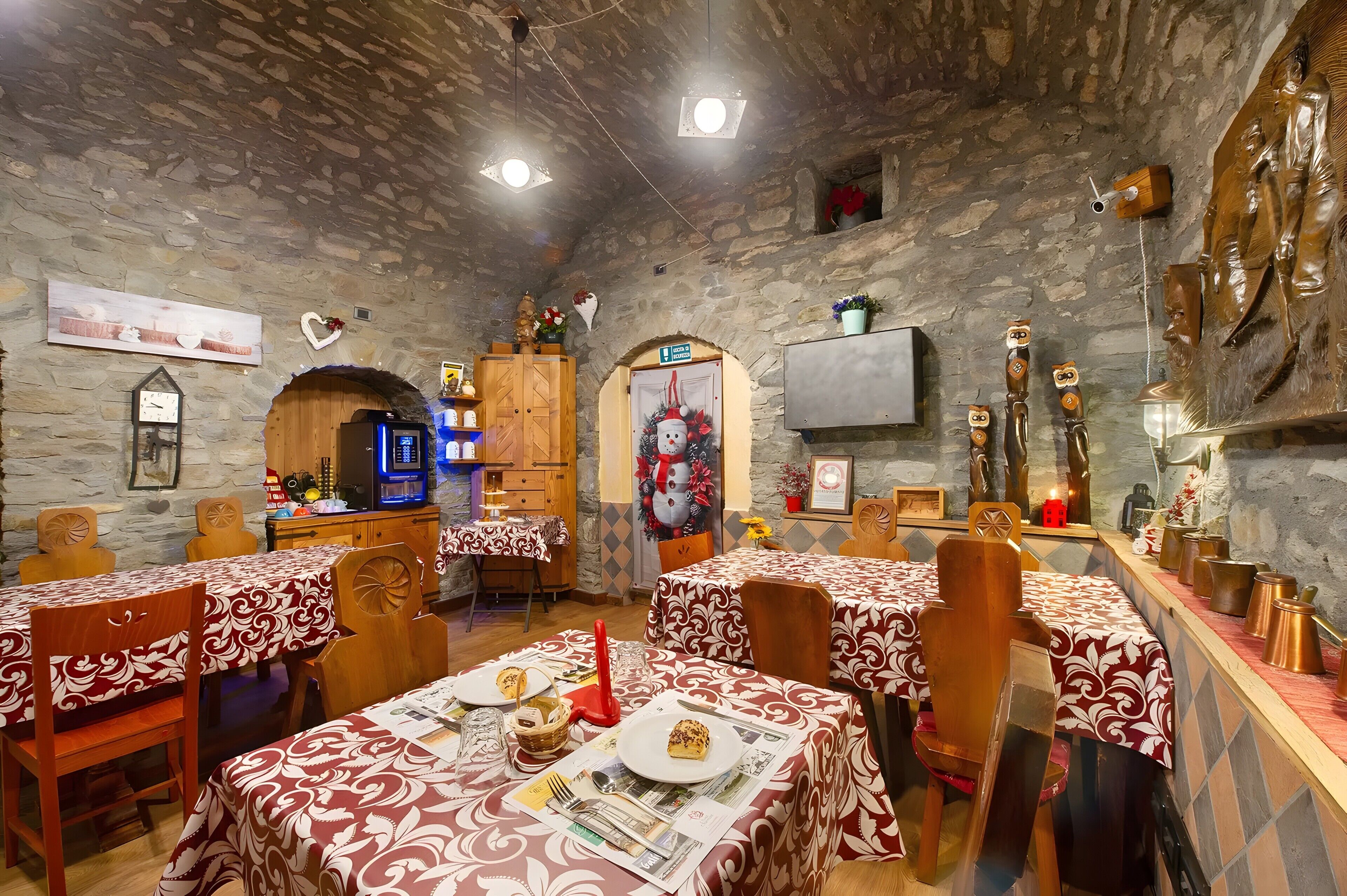 Un intérieur rustique avec des murs en pierre, des meubles en bois et des tables dressées pour le repas.