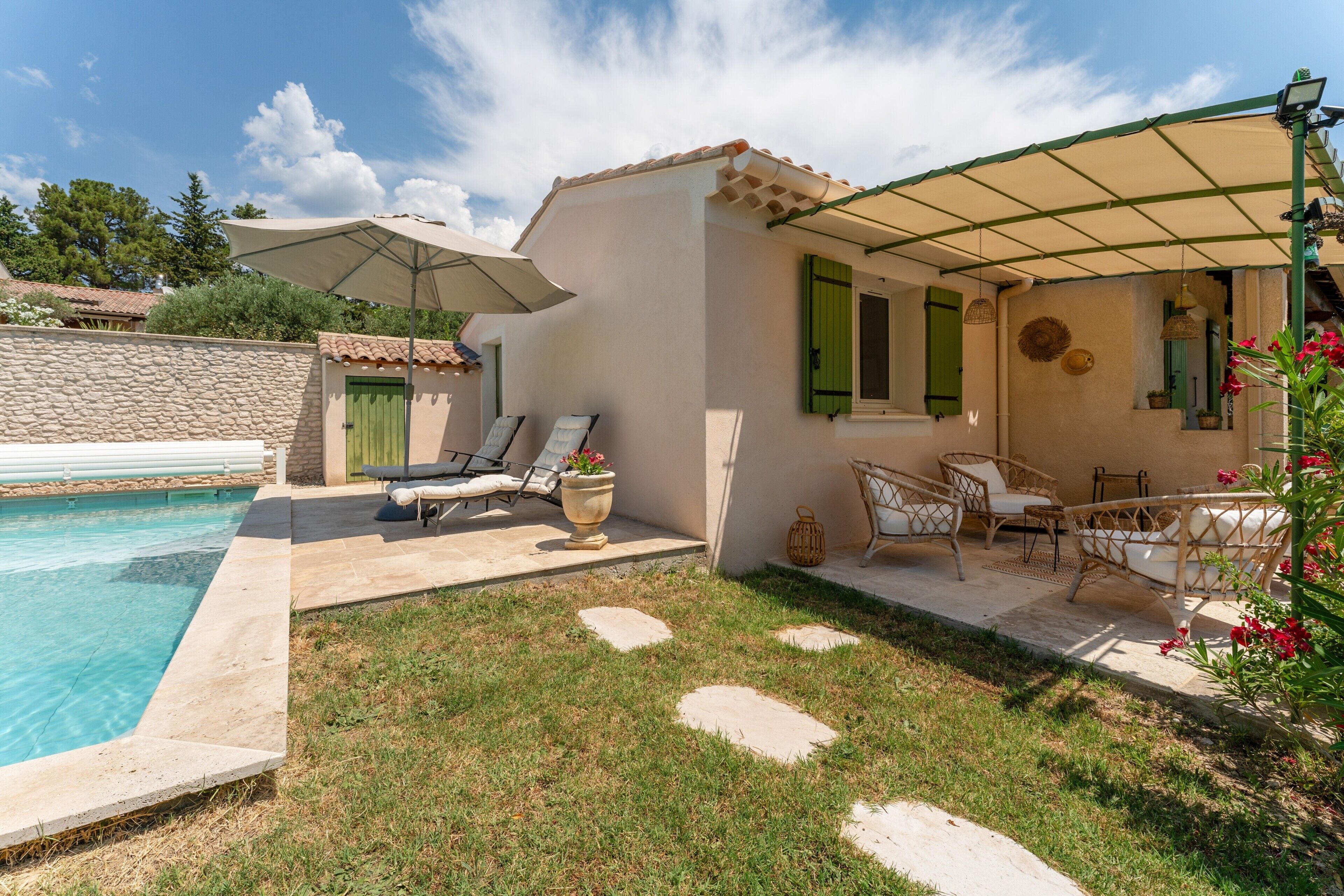 Un espace aménagé au bord de la piscine, avec un patio couvert, des chaises longues et une petite table.