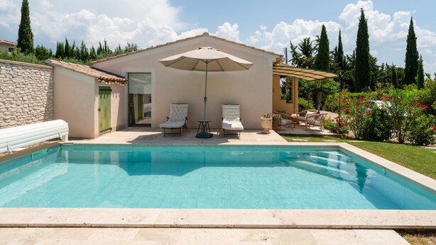 A swimming pool with lounge chairs, a pergola with an umbrella, and a stone wall. - Lou Cigaloun Holiday Home with Private Pool, Wi-Fi, and Air Conditioning (Bédoin)