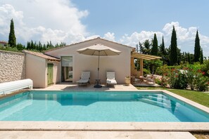 A swimming pool with lounge chairs, a pergola with an umbrella, and a stone wall. - Holiday Home “Lou Cigaloun” with Private Pool, Wi-Fi & Air Conditioning (Bédoin)