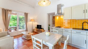 A kitchen with white cabinets, a yellow backsplash, and a dining area with a table and chairs. - Lou Cigaloun Holiday Home with Private Pool, Wi-Fi, and Air Conditioning (Bédoin)