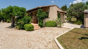 A house with a gravel driveway, a front porch, and a garden with various plants and trees. - Lou Cigaloun Holiday Home with Private Pool, Wi-Fi, and Air Conditioning (Bédoin)