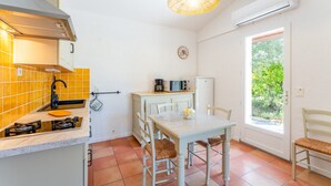A compact kitchen with a gas stove, a sink, and a dining table with chairs. - Lou Cigaloun Holiday Home with Private Pool, Wi-Fi, and Air Conditioning (Bédoin)