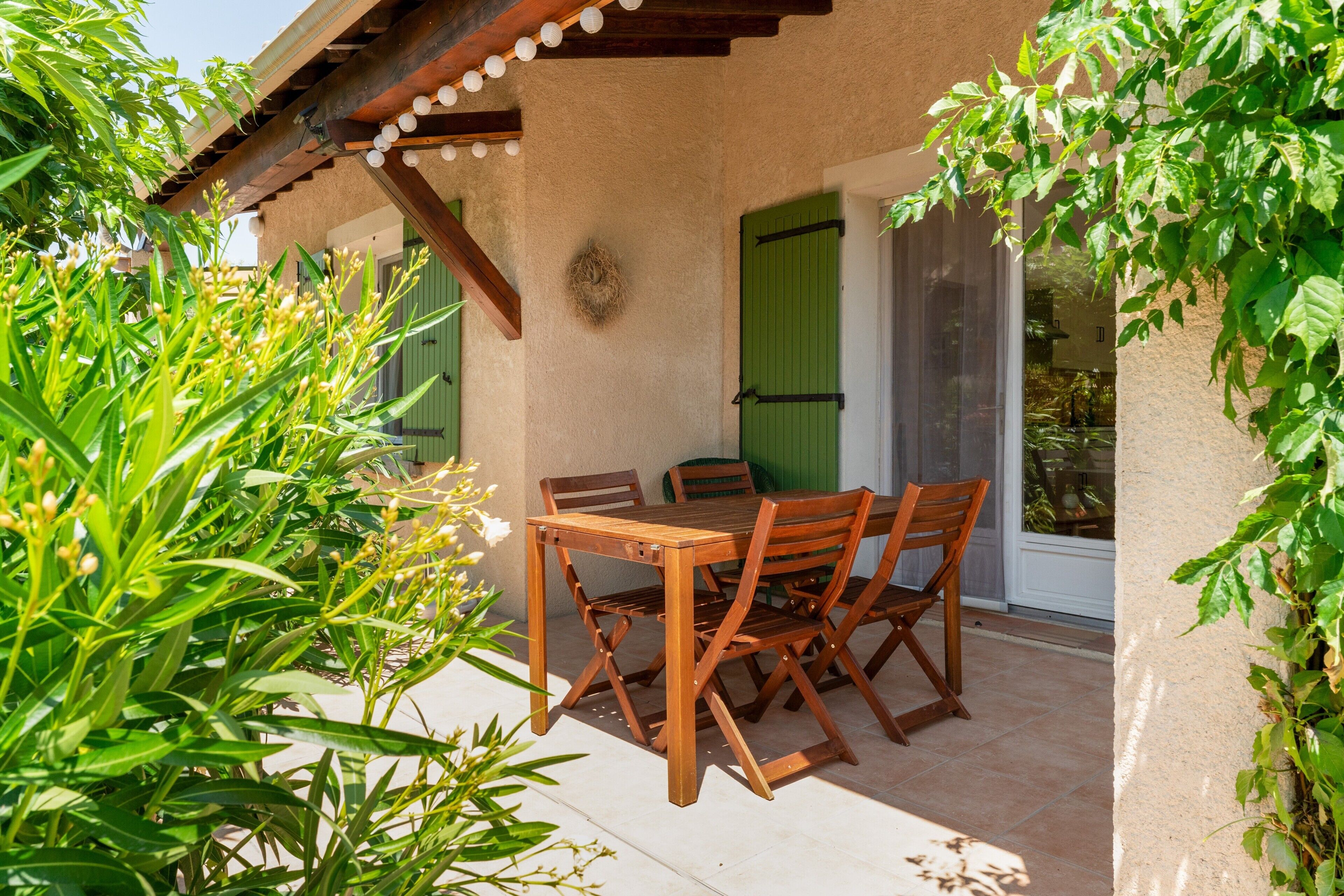 A wooden table and chairs set on a patio with a pergola overhead.