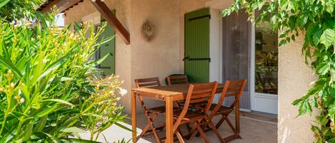 A wooden table and chairs set on a patio with a pergola overhead.