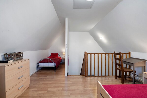 A bedroom with a loft bed, a desk, a chair, and a wooden dresser.