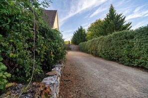 A gravel driveway leading to a house with a stone wall on one side and dense foliage on the other. - Maison Montagnac – Peaceful Retreat with Garden in the Heart of the Lot (gignac)