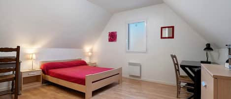 Une petite pièce bien éclairée, avec un lit, des tables de chevet, un bureau et une chaise.