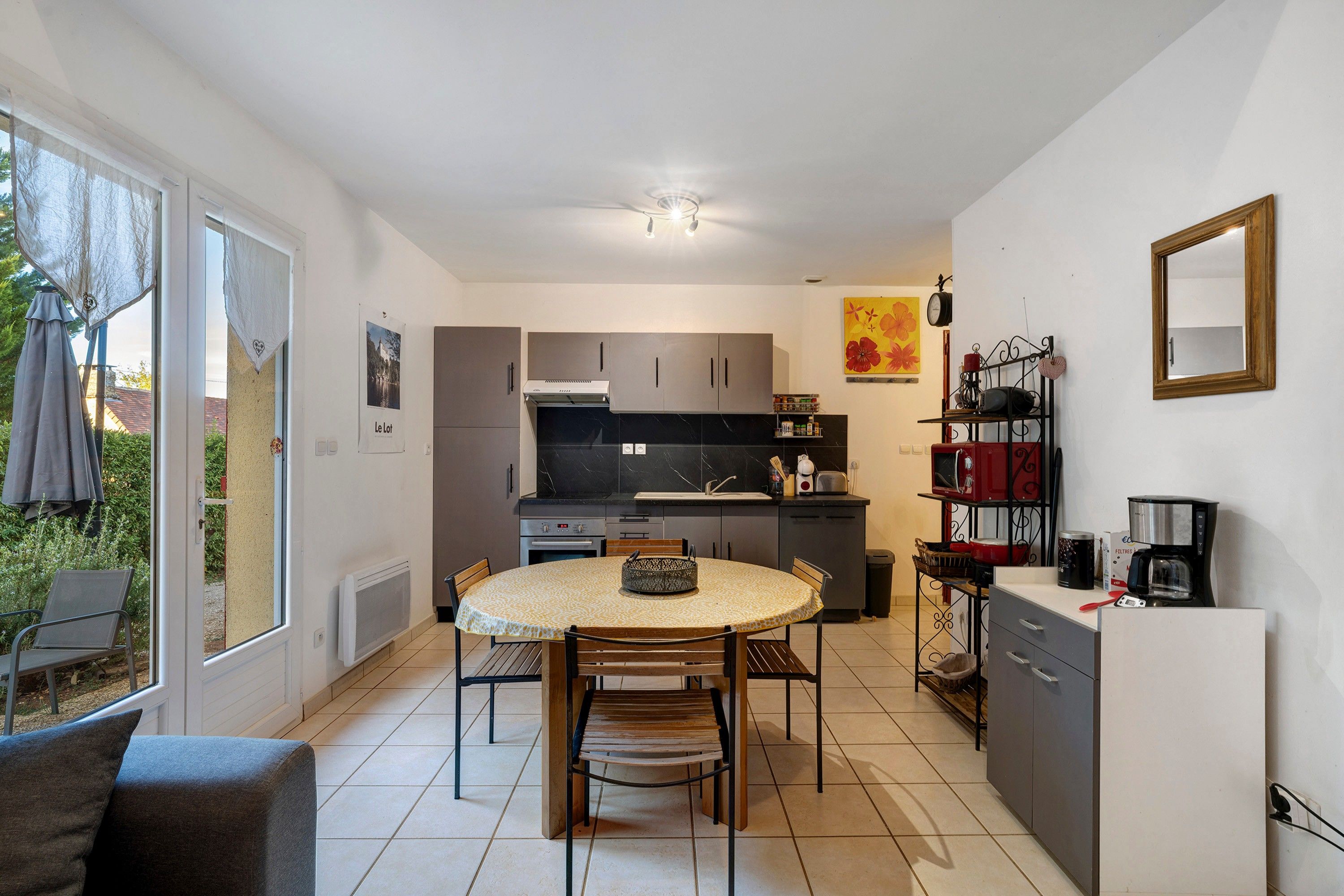 Een kleine keuken met een eettafel, stoelen en een kleine koelkast.