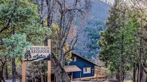 A rustic cabin named River Haus Sequoia surrounded by dense forest and mountains. - River Haus Sequoia | Hot Tub+New+King Beds+Views! - Holiday Home (Springville)