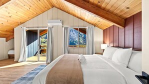 A bedroom with a large bed, wooden ceiling, and a view of trees through the window. - River Haus Sequoia | Hot Tub+New+King Beds+Views! - Holiday Home (Springville)