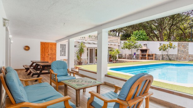 Un espace extérieur aménagé, abrité et doté de mobilier en bois, ainsi qu’une piscine.