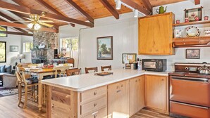 A spacious kitchen with wooden cabinets, a central island, a microwave, and a stove. - Cedar Pine Cottage | Relaxing Cozy 2BR Cabin (Springville)