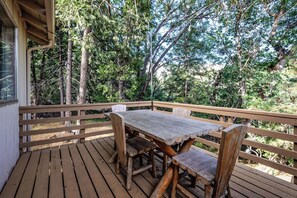 Una terraza de madera con una mesa y sillas, rodeada de árboles.