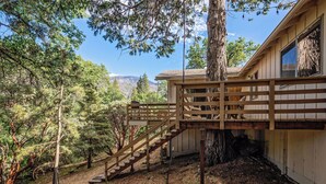 A wooden staircase leading to a cabin with a view of a forest and mountains in the background. - Cedar Pine Cottage | Relaxing Cozy 2BR Cabin (Springville)