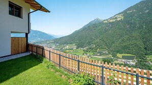 A house with a wooden fence, a window, and a view of a valley with mountains.