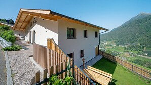 A white building with a wooden deck and a mountain view.