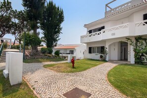 A courtyard with cobblestone paths, a red fire hydrant, and a white building with a balcony. - Apartment 'Tennis View' with Private Pool, Wi-Fi and Air Conditioning (Almancil)